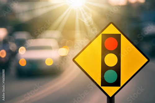 Traffic light warning sign on blur traffic road with colorful bokeh light abstract background.