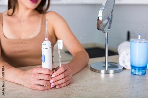 Woman with a toothbrush and an oral irrigator