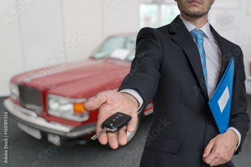 Salesman is selling a new car and passing keys.