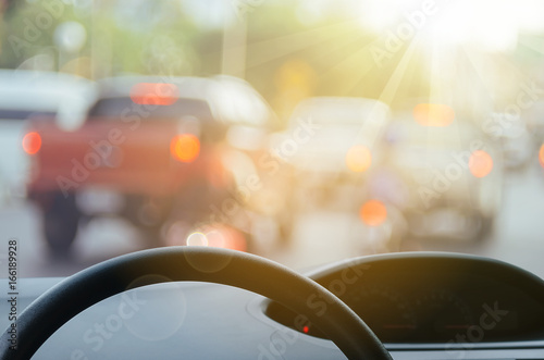 Inside car view ,steering wheel on blur traffic road with colorful bokeh light abstract background.