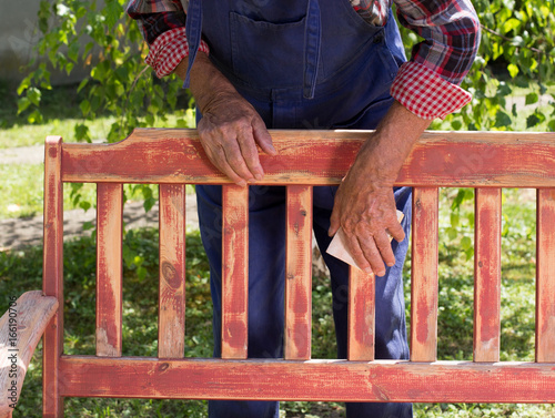 Foto Old man sandblasting bench in garden