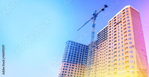 Multi-storey building under construction. Building. Unfinished house. Lifting crane. The concept of development. Toned photo.