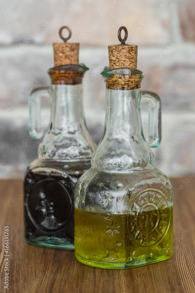 Oil and balsamic vinegar glass bottles with spouts on rustic brick wall background Oil and balsamic vinegar glass bottles with spouts on rustic brick wall background