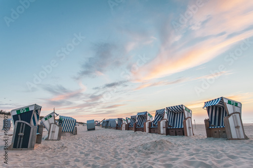 Beach chairs on the island Nordernery in the North Sea during the sunset photo