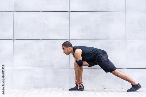 african american runner stretching on street