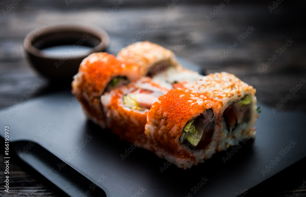 close up of sushi rolls on black tray and dark wooden table close up of sushi rolls on black tray and dark wooden table