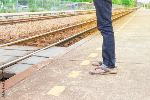 Fototapeta Naklejka Na Ścianę i Meble -  leg male of travel put jeans stand wait train in station  trail platform with copy space with sun light yellow