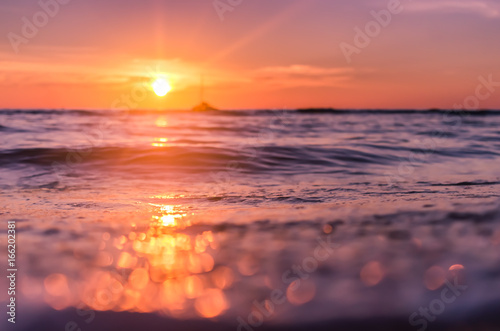 Blur tropical sunset beach with bokeh sun light wave abstract background. © tonktiti