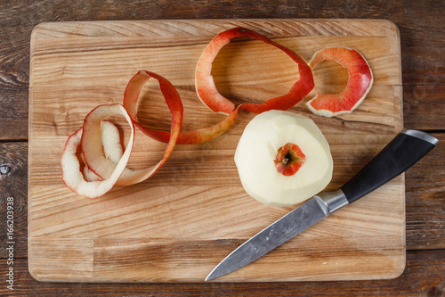 Top view of single red apple paring by knife. Fresh fruit lay on wooden desk. Healthy food, dietary, cooking concept photo