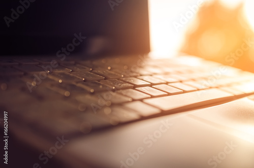 Business economic and technology working concept. Close up keyboard notebook with window light bokeh abstract background.