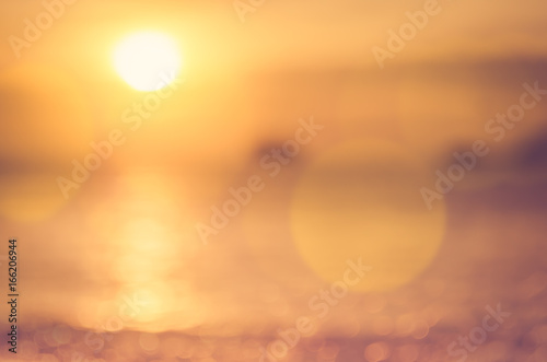 Blur tropical sunset beach with bokeh sun light wave abstract background.