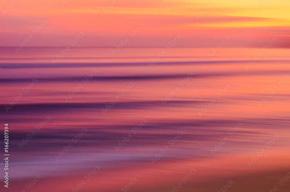 Motion blur tropical sunset beach with bokeh sun light wave abstract background.