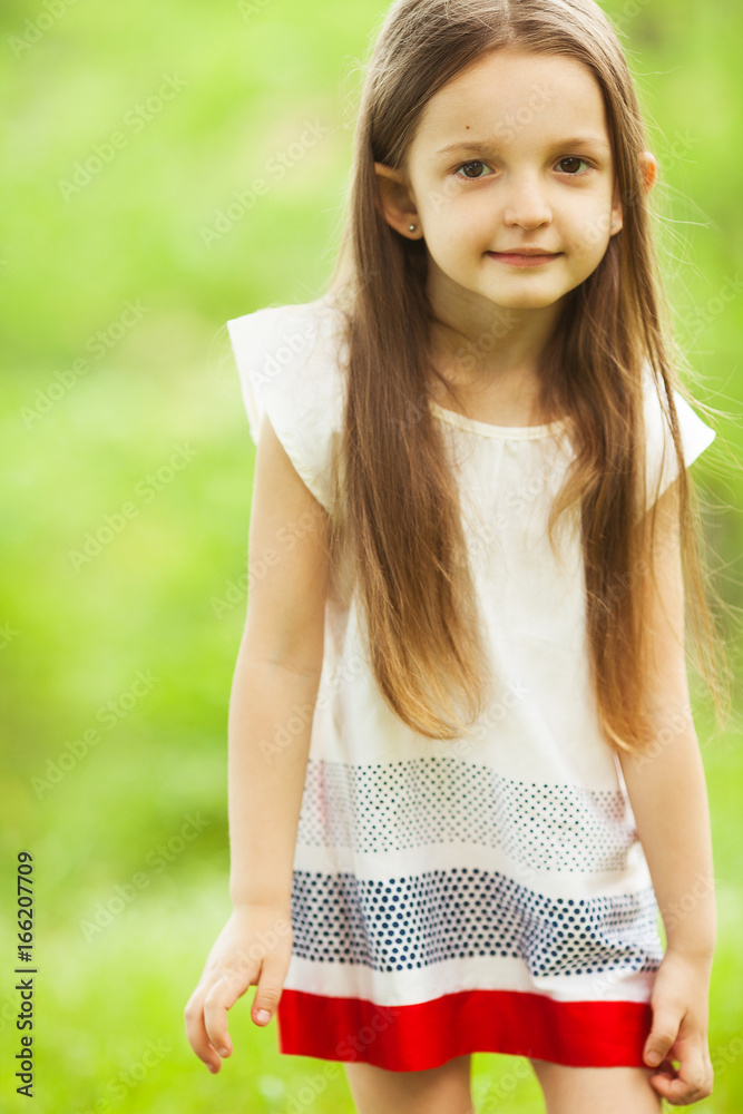 Stylish baby girl with long light brown hair in trendy vintage red and  white dress standing in the park and smiling. Hipster style. Sunny weather.  Outdoor shot Stock Photo | Adobe Stock