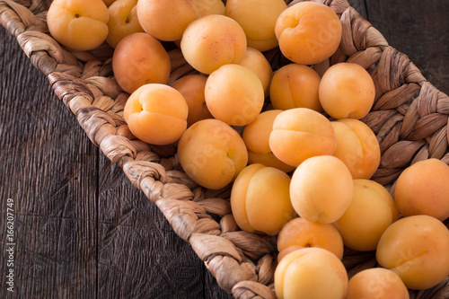 Delicious ripe apricots in a wooden bowl on the table close-up. photo