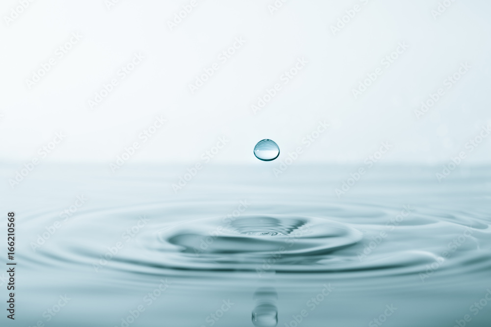 Water drop and splash on water surface on blue background Water drop and splash on water surface on blue background