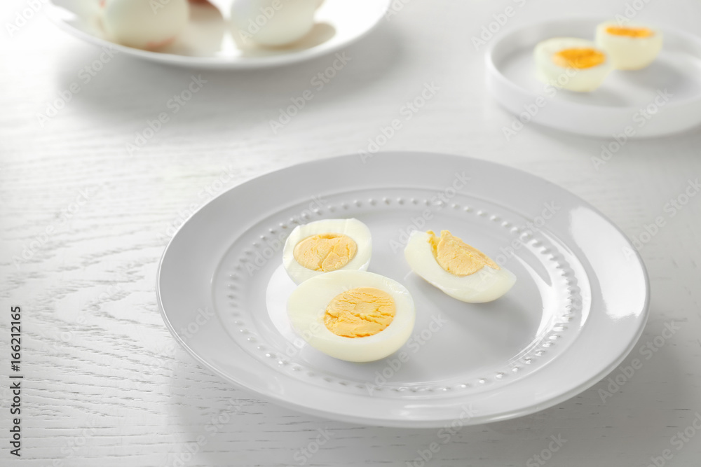 White ceramic plate with sliced hard boiled eggs on wooden table. Nutrition concept White ceramic plate with sliced hard boiled eggs on wooden table. Nutrition concept