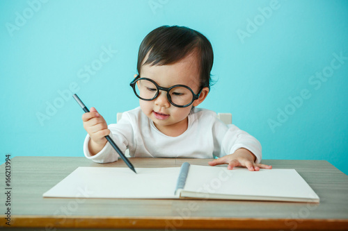 Portrait of an adorable baby girl wearing glasses on the table (soft focus on the eyes) photo