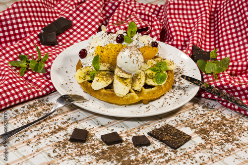 Dessert with pieces of banana, peach and ice cream sprinkled with grated chocolate. Dessert of shortcake with fruit. Cake with fruit and ice cream.