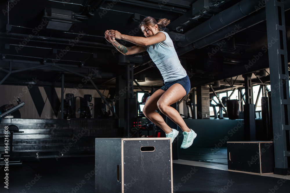 Sporty girl jumping over some boxes in gym