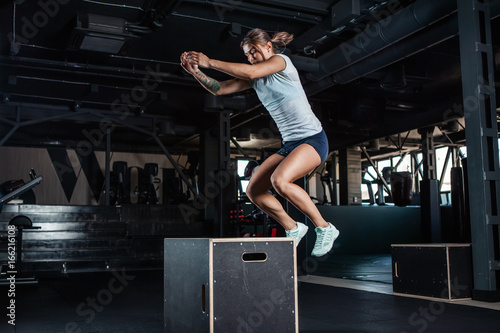 Obraz na płótnie Sporty girl jumping over some boxes in gym w salonie