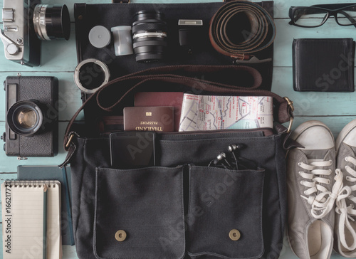 travel concept, Outfit of traveler with retro camera film, vintage bag, notebook, passport, glasses, sneaker, Belt, smartphone on wooden background, vintage tone style photo