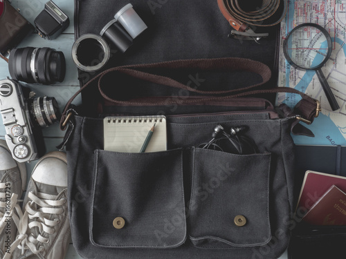 travel concept, Outfit of traveler with retro camera film, vintage bag, notebook, map, passport, glasses, sneaker, Belt, smartphone on wooden background, vintage tone style