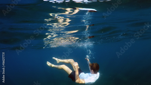 young man sinking into the sea © Photobank