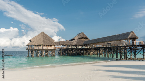 beautiful wooden pier with thatched huts in ocean © tan4ikk