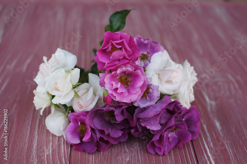 Bouquet of pink and purple garden roses on a wooden background © Olga Tkacheva