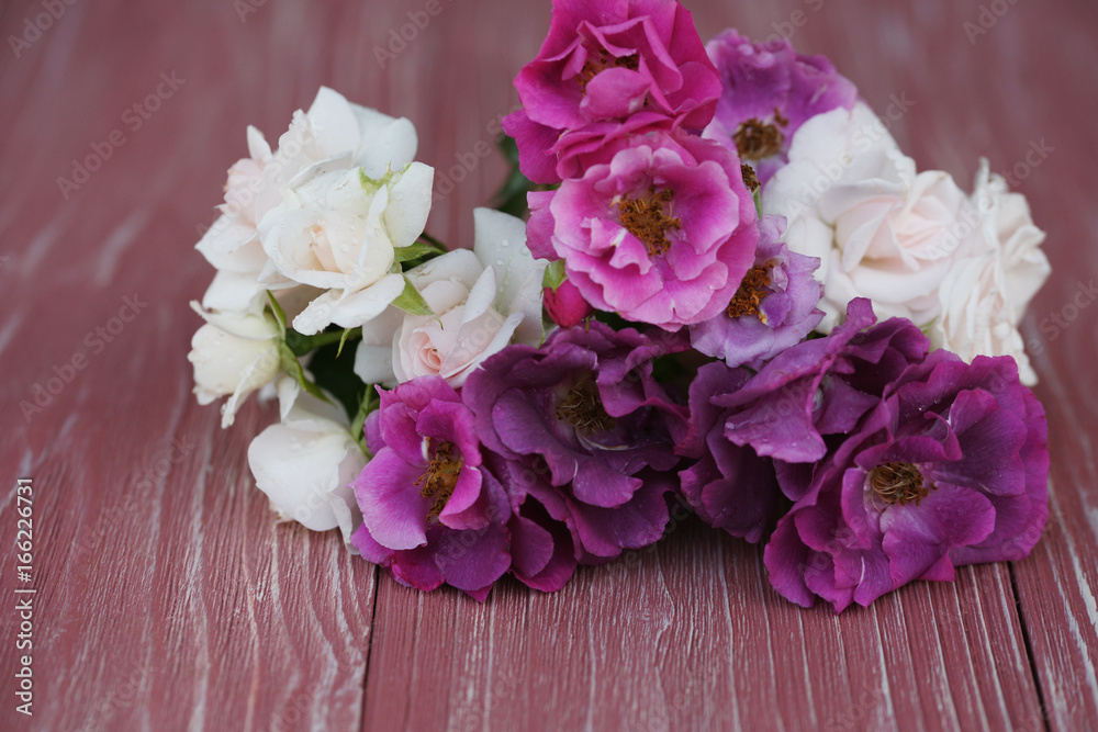 Bouquet of pink and purple garden roses on a wooden background Bouquet of pink and purple garden roses on a wooden background