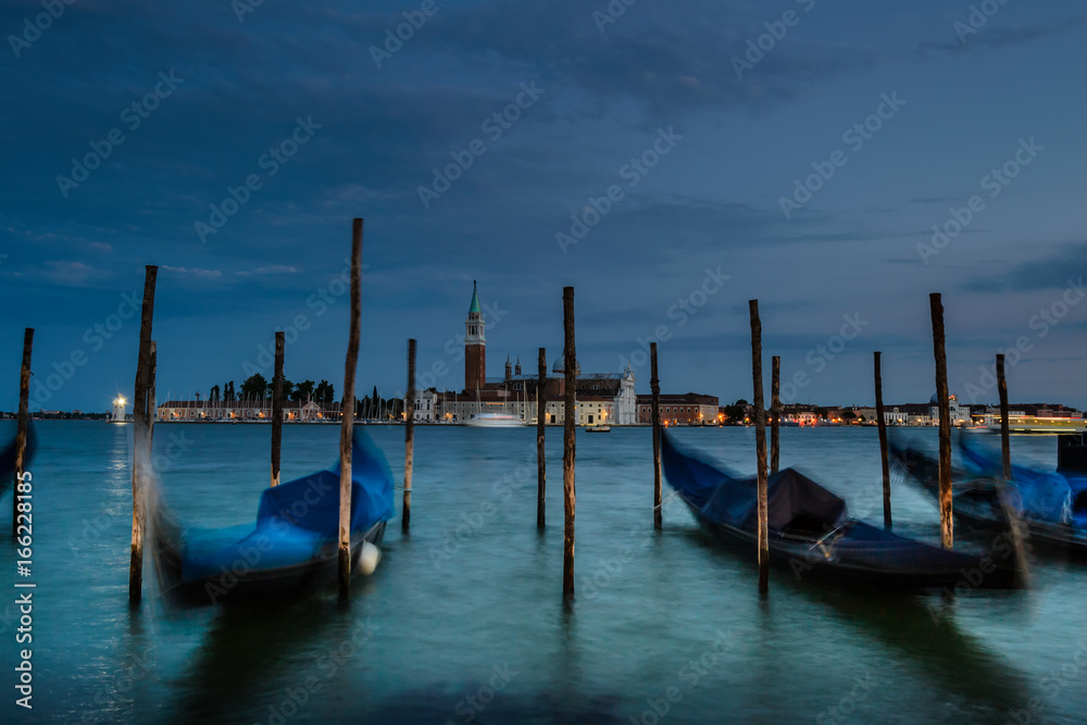 Gondeln vor der Kirche San Giorgio während der Dämmerung in Venedig