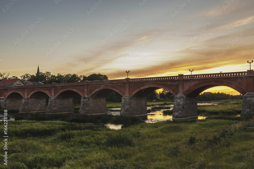 Fototapeta premium The old-fashioned Latvia.Kuldiga. ventas hub over the bridge at night