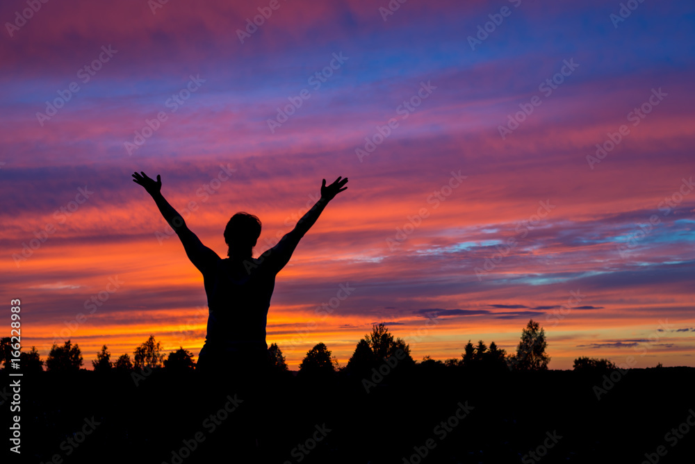Man with hands up silhouette with colorful sunset