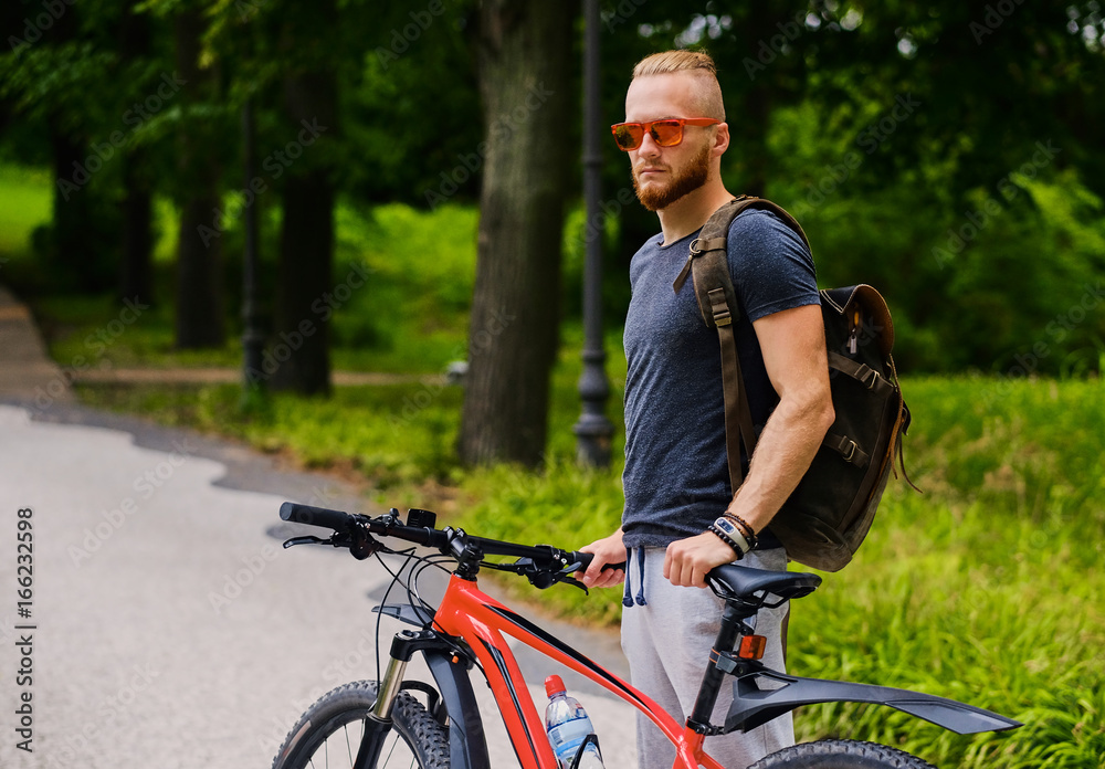 Obraz premium A man sits on a red mountain bicycle outdoor.