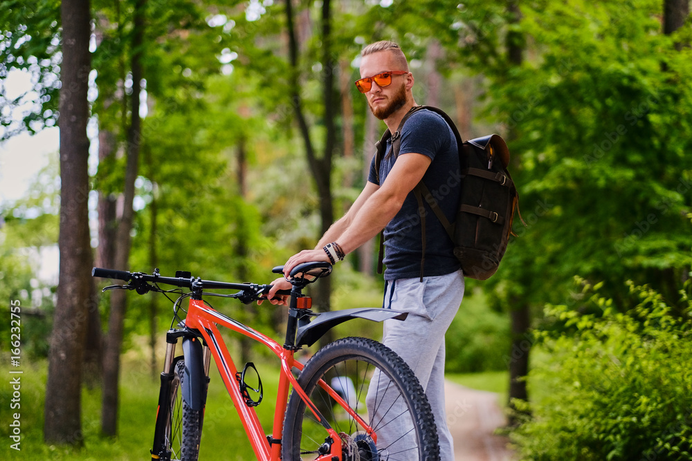 A man sits on a red mountain bicycle outdoor. A man sits on a red mountain bicycle outdoor.