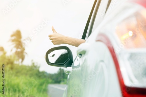 Atmosphere air is refreshing in the sunshine. Young woman hand show thumbs up Drive out on the road on holiday. photo
