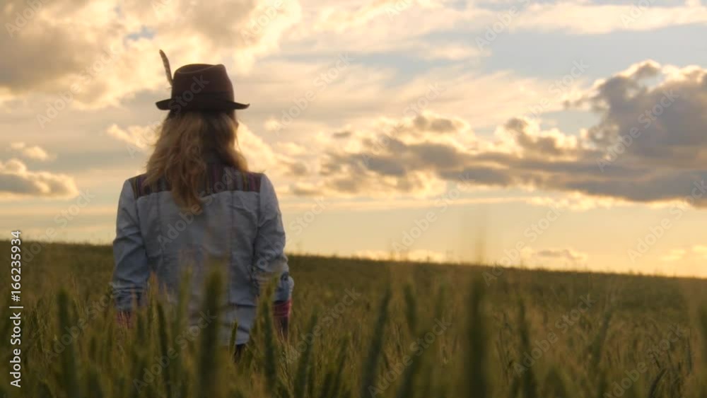 Bohemian woman standing in barley field watching sunset Bohemian woman standing in barley field watching sunset