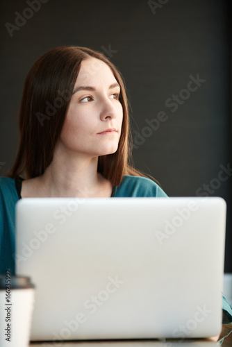 Young woman working on laptop while sitting at cafe