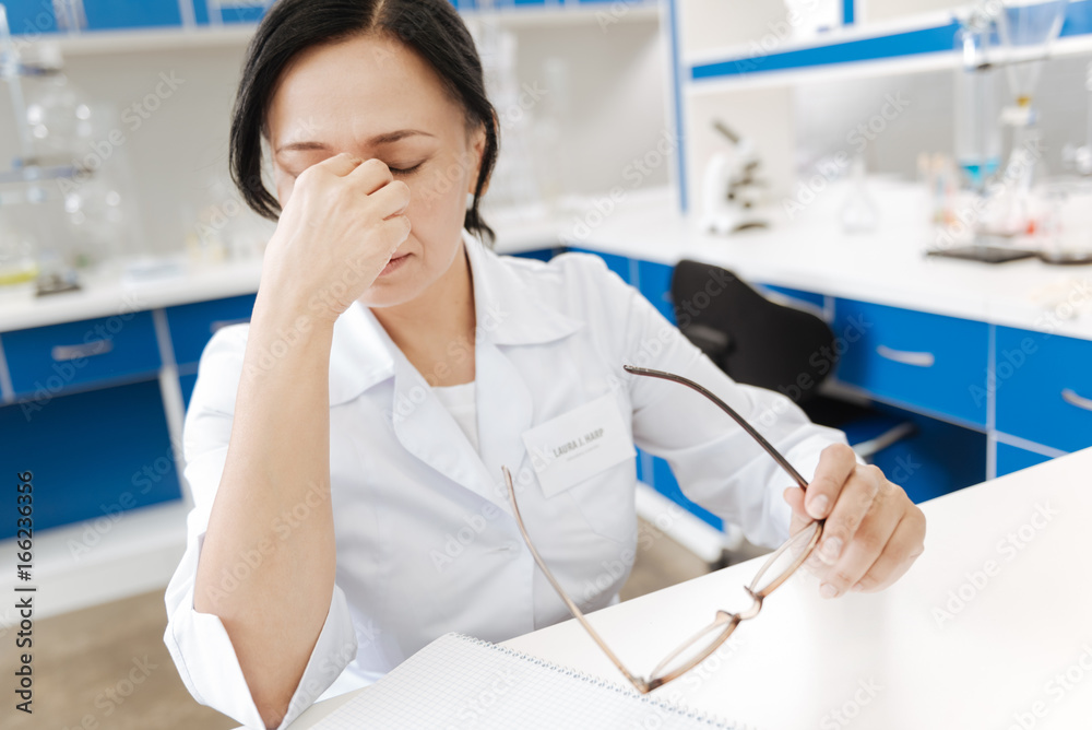 Tired female scientist sitting at the table Tired female scientist sitting at the table
