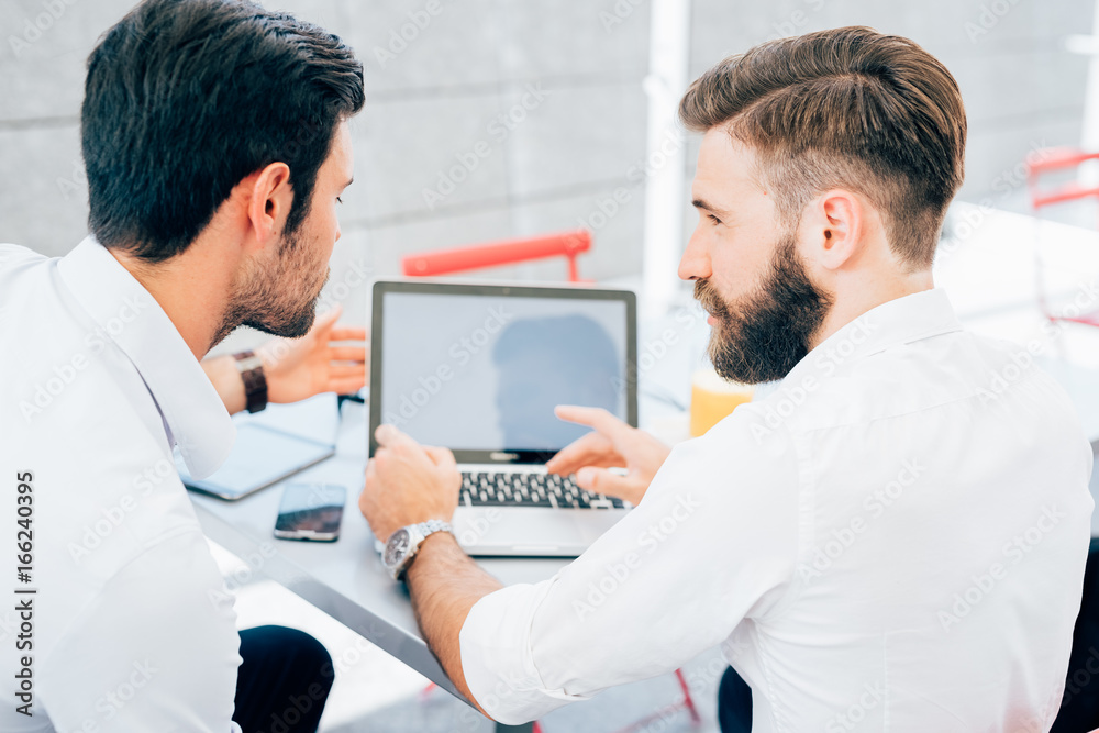 back view of two bearded business men young outdoor using computer - remote working, business, marketing concept back view of two bearded business men young outdoor using computer - remote working, business, marketing concept