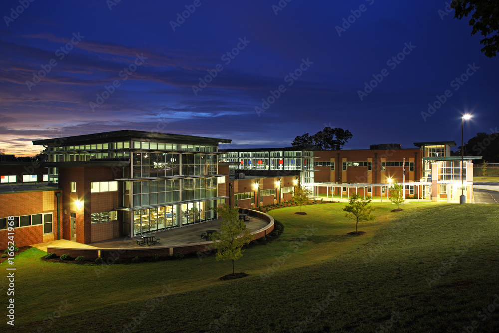 Naklejka premium Generic High School Building Exterior at Sunset with Glass Windows During Night Time