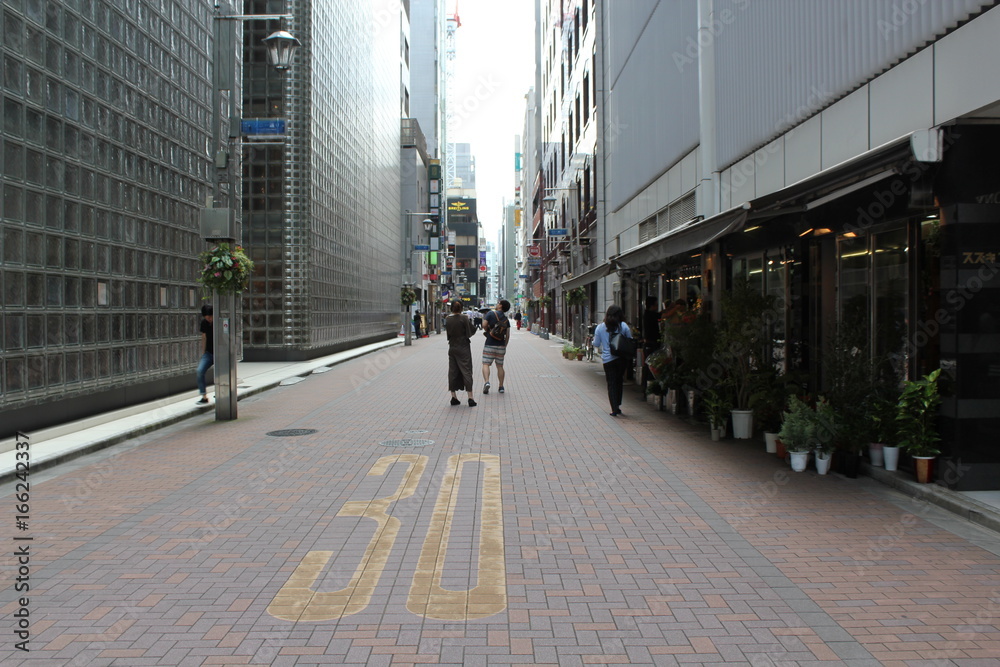 People walking on the street in tokyo near to maison hermes by renzo piano architecture
