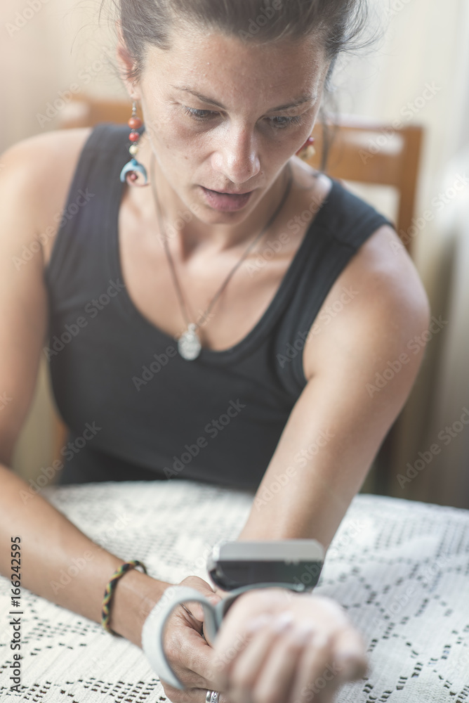 Naklejka premium Young woman measuring blood pressure at home