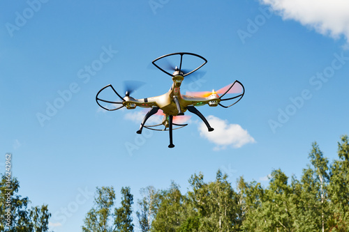  quadrocopter drone in flight against a blue sky.