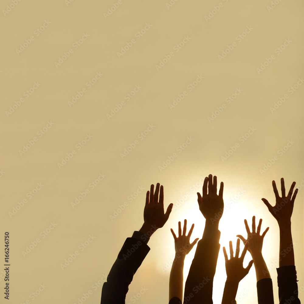 silhouette of  diverse people hands rised up on hot light background