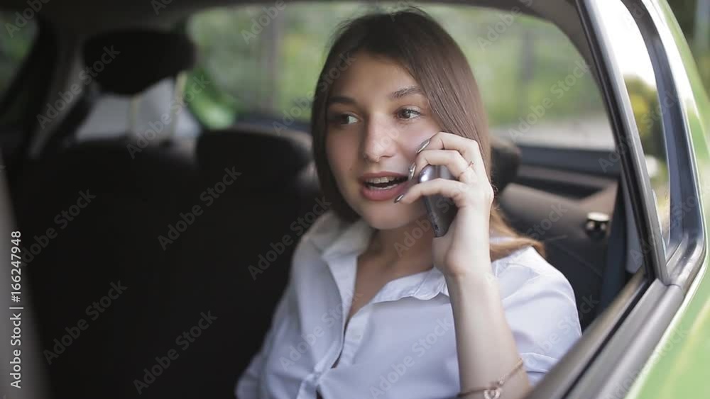Girl in the back seat of the car talking on the phone Girl in the back seat of the car talking on the phone