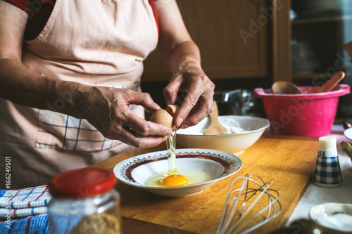Close up of female baker hands preparing eggs for dough.