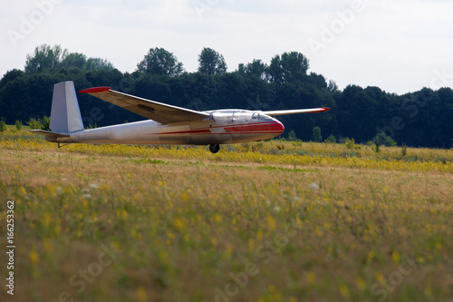 Glider landing after flight in blue sky