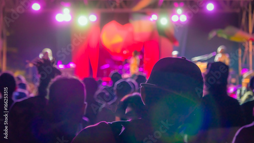 Silhouette of man in the crowd in baseball cap on reggae concert bright lights with lens flare © DarwelShots