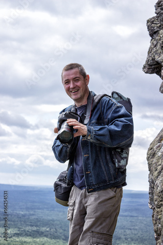 Professional photographer takes photos on the peak of rocks mountai
